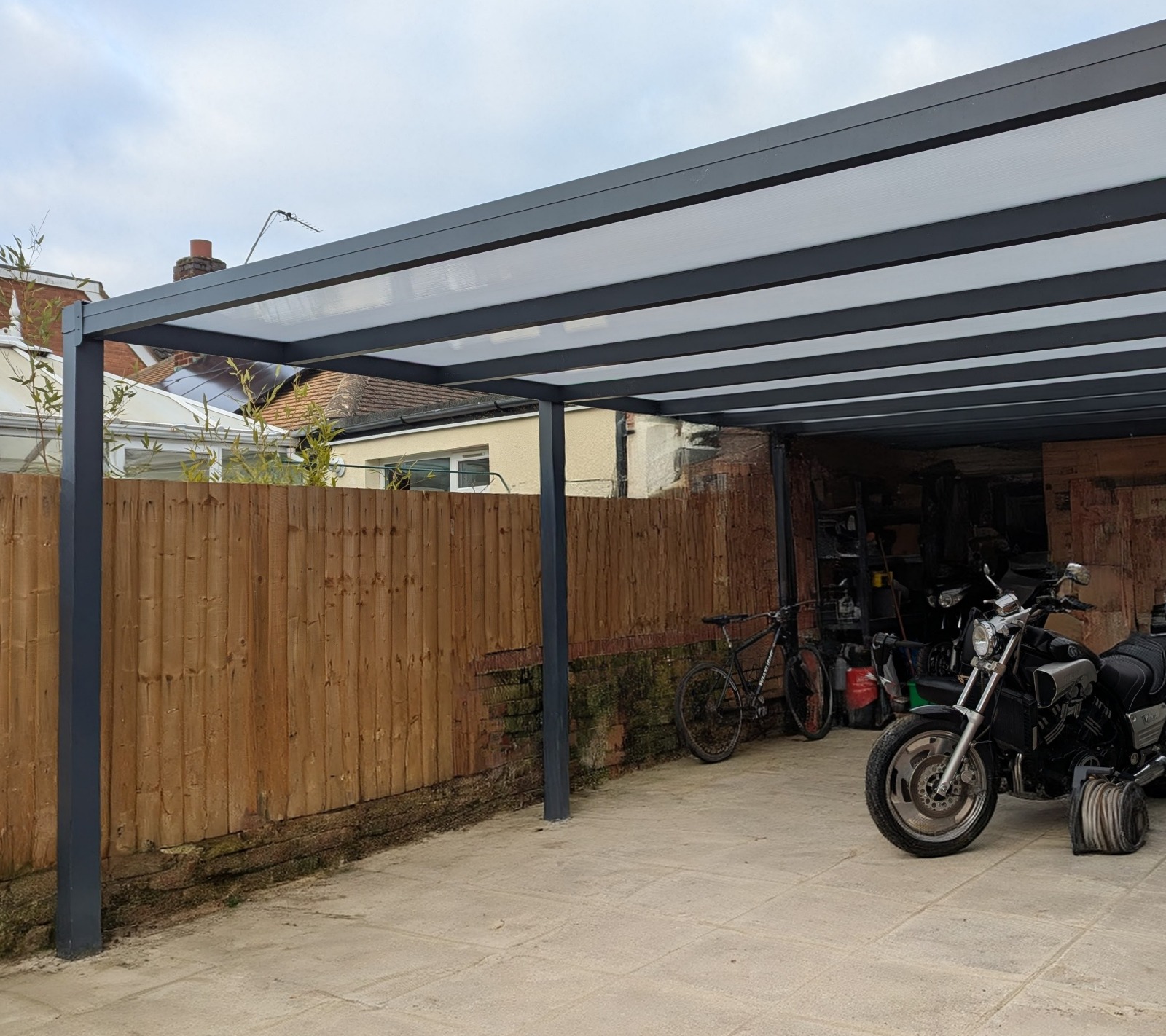 A modern aluminium carport with motorbikes parked underneath