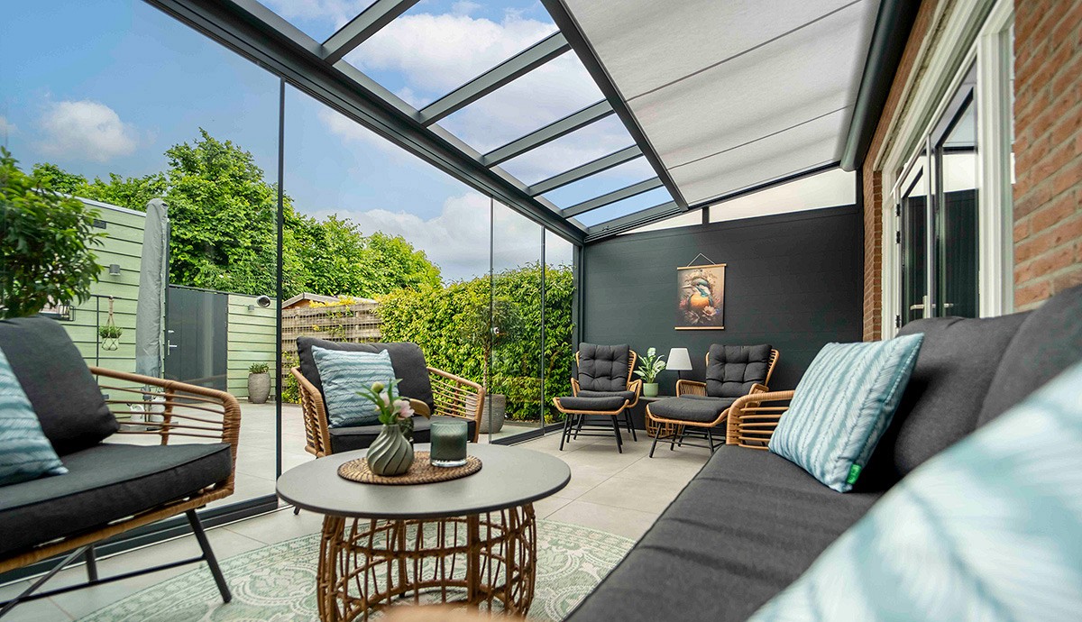 A bright glass garden room interior with sectional sofa and views of the garden