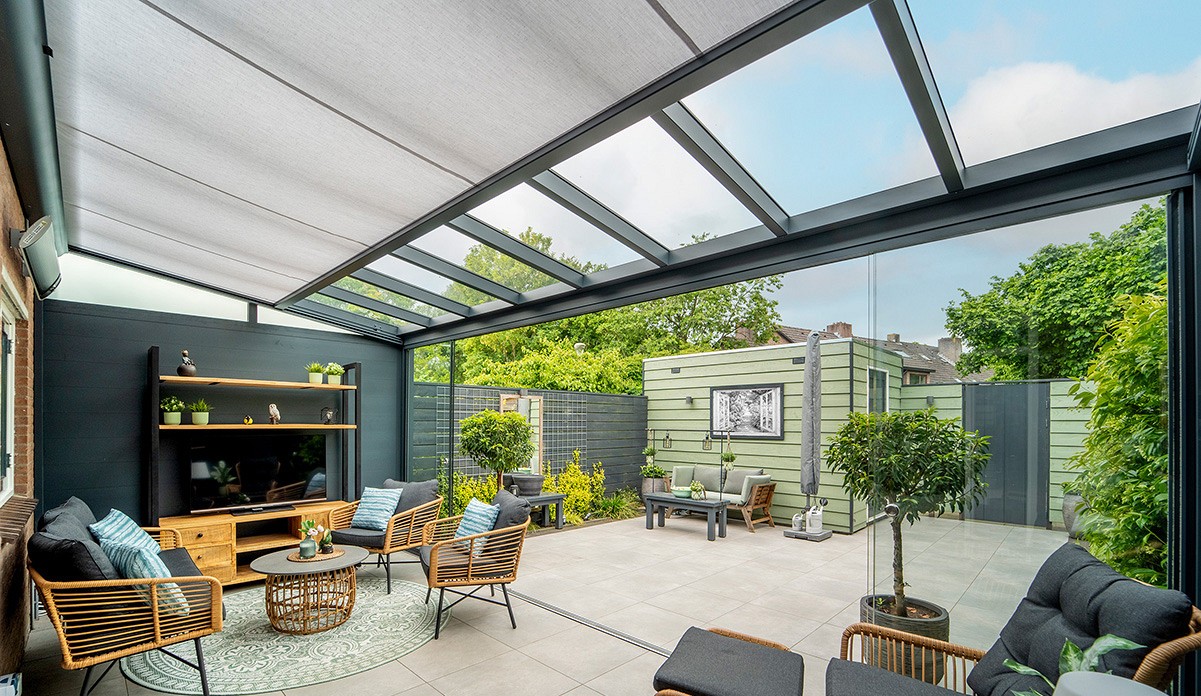 Bright glass garden room interior with sliders, sectional sofa, dining table and views to the garden