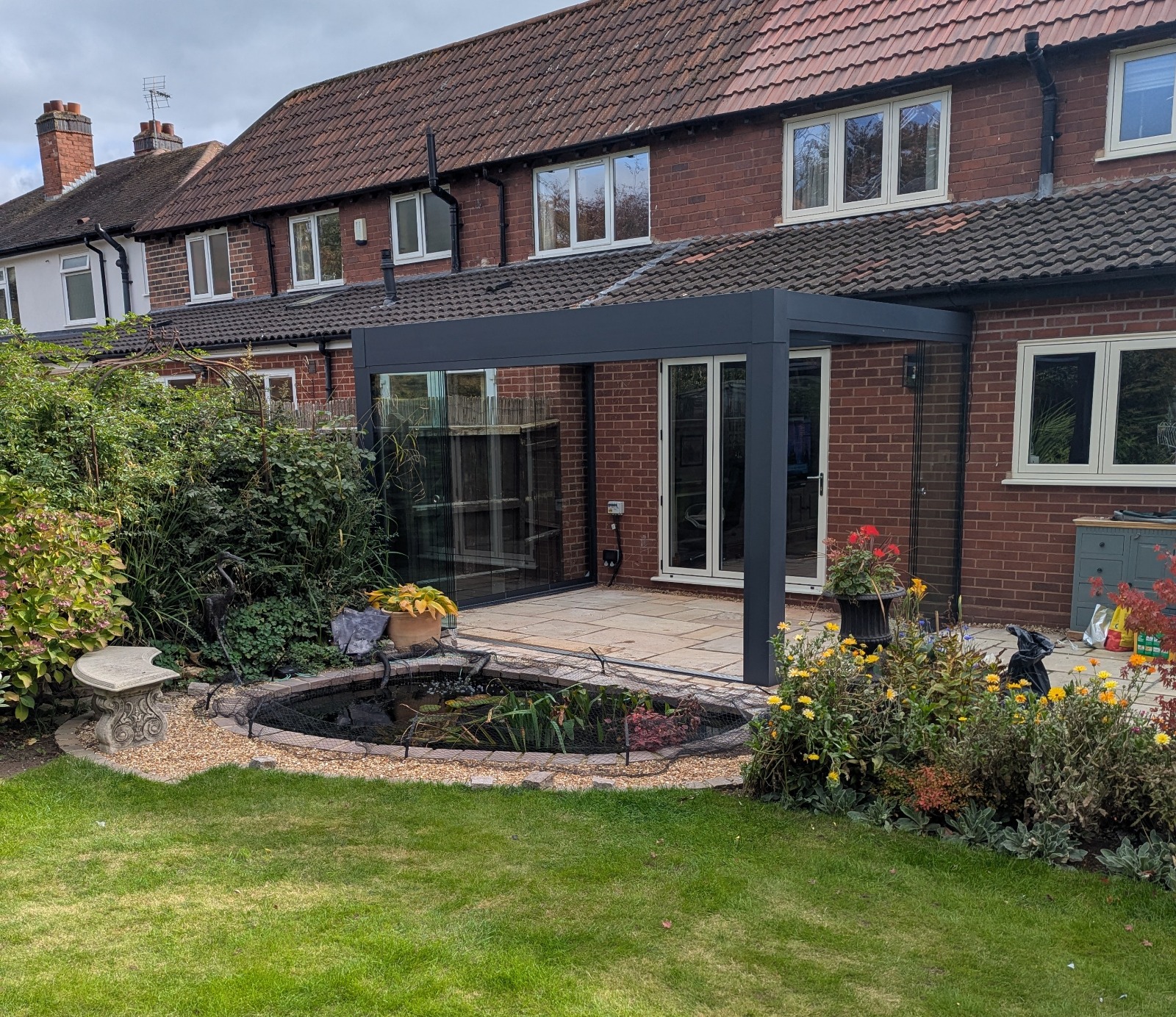 A compact polycarbonate veranda over a small patio with garden pond