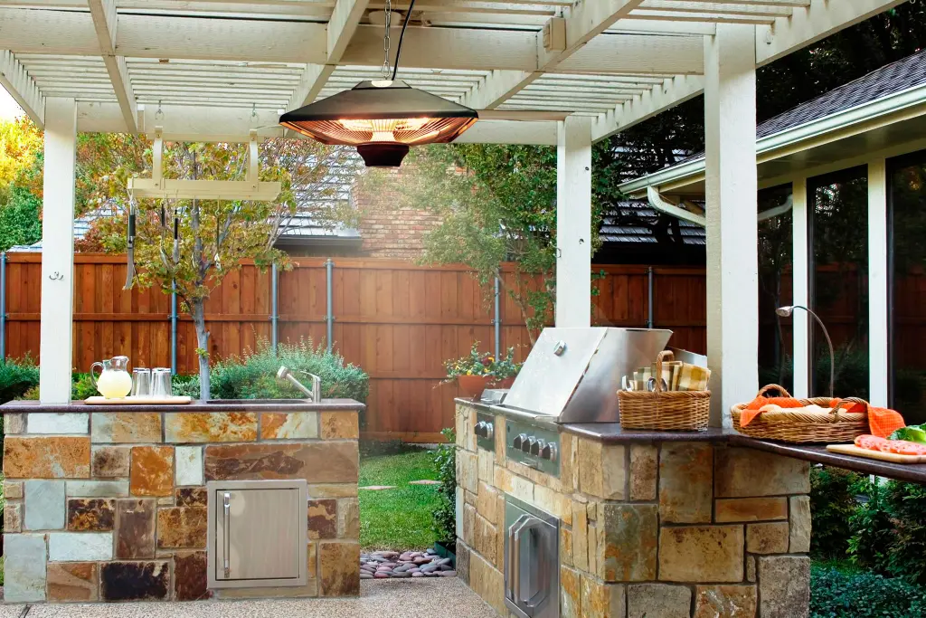 Outdoor kitchen and dining area beneath a covered pergola