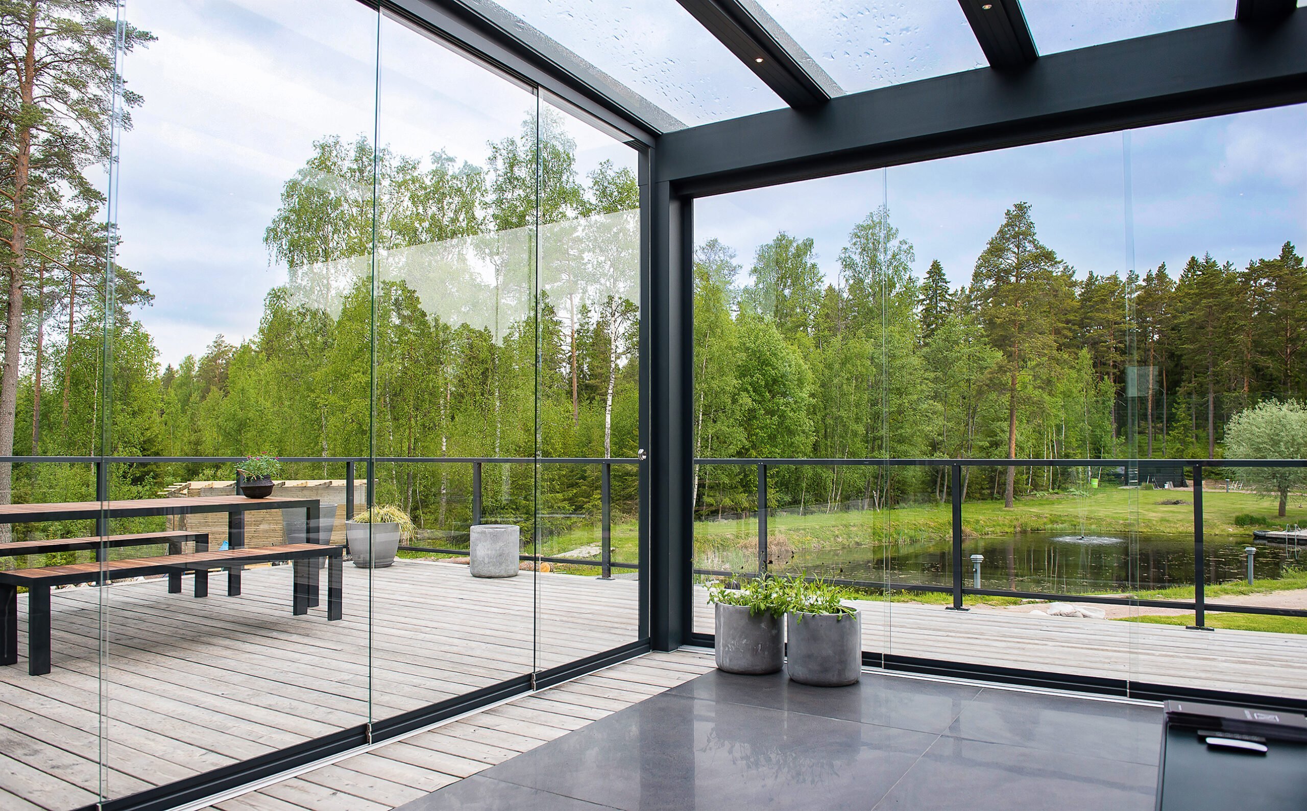 Glass garden room interior with views over a forest and pond