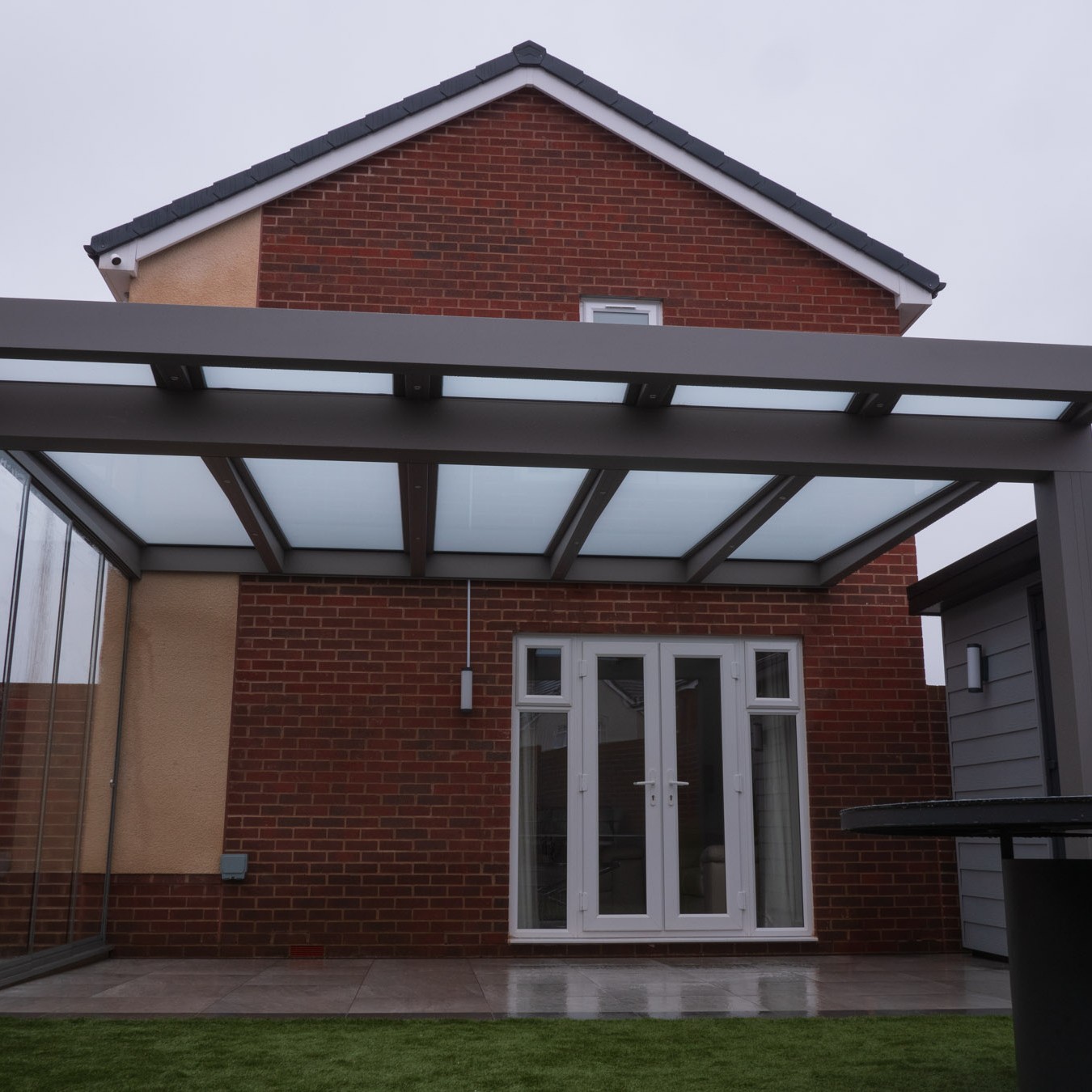 Silver-bronze CubeLine veranda with a polycarbonate roof over a patio