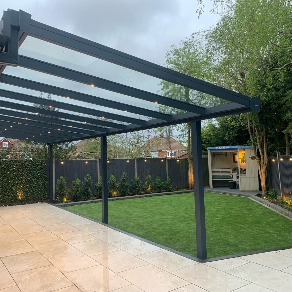 Anthracite-grey ProLine Slim veranda with a glass roof and sliding glass sides