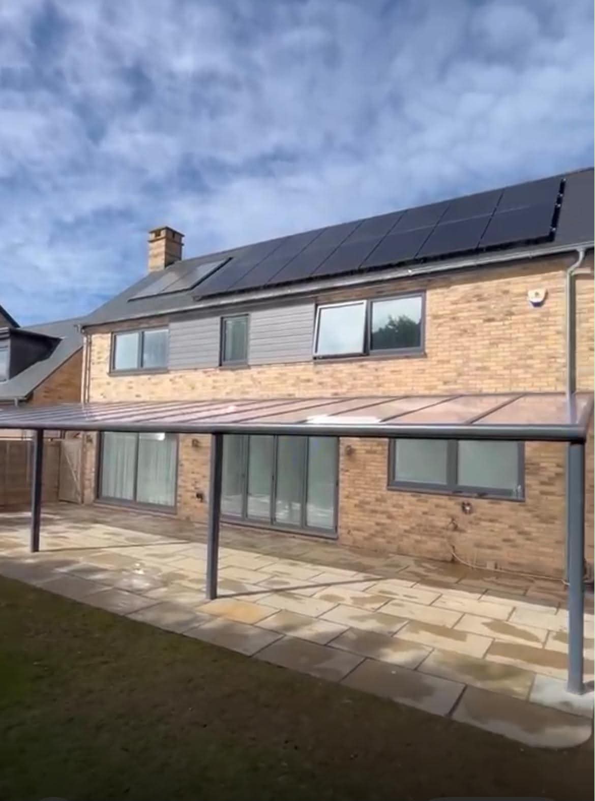 Bordeaux polycarbonate veranda with a bronze translucent roof over a paved patio, attached to a brick house